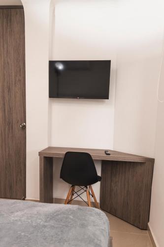 a bedroom with a desk and a television on a wall at Hotel Boutique Business Center in Cali