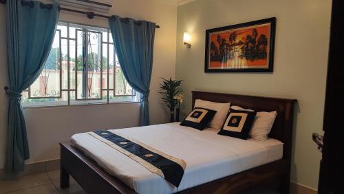 a bedroom with a bed with blue curtains and a window at Le Watwam Hotel in Siem Reap