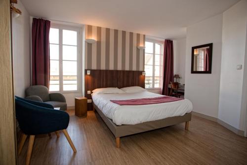 a bedroom with a bed and a chair and windows at Hôtel Océan Dinan in Dinan