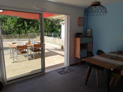 une porte coulissante en verre menant à une terrasse avec une table. dans l'établissement VILLA HÉLIOS, à Jard-sur-Mer