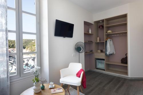 a living room with a white chair and a window at Best Western Hotel du Roy d'Aragon in Bonifacio