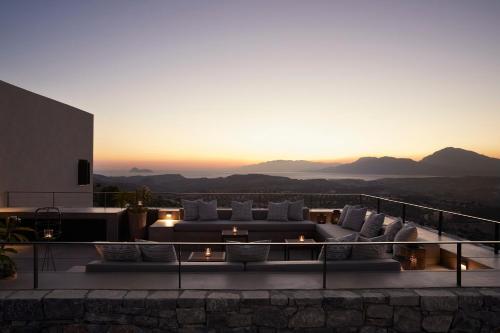 a living room with couches and a sunset at Askianos Luxury Villas - An Oasis of Harmony & Elegance in Lístaros