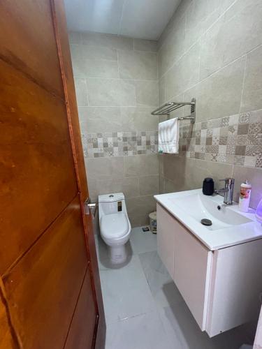 y baño con aseo y lavamanos. en Acogedor Apartamento Familiar con piscina., en Boca Chica