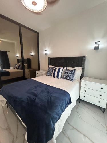 1 dormitorio con 1 cama grande y espejo en Acogedor Apartamento Familiar con piscina., en Boca Chica