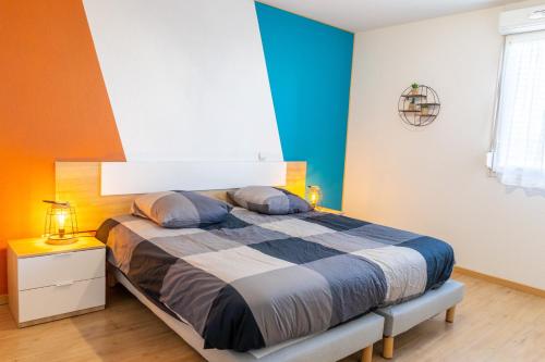 Schlafzimmer mit einem Bett mit blauen und orangefarbenen Wänden in der Unterkunft Le Beluga – Appartement proche Airbus in Colomiers