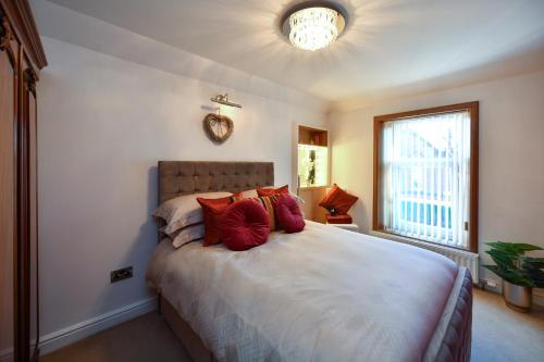 a bedroom with a large bed with red pillows at The Lemon Tree in Prestwick