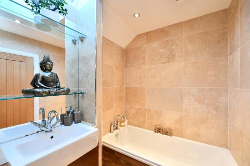 uma casa de banho com um lavatório, uma banheira e uma estátua. em The Lemon Tree em Prestwick