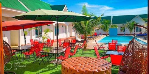 een groep tafels en stoelen met parasols en een zwembad bij Sunrise Villas in Jambiani
