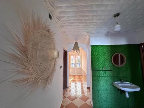 a bathroom with a sink and a green wall at Olas Surf House in Imsouane