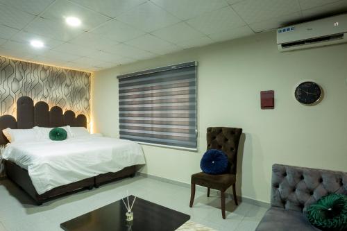 ein Schlafzimmer mit einem Bett, einem Stuhl und einem Tisch in der Unterkunft VIDDOSH RESIDENCE in Ibadan