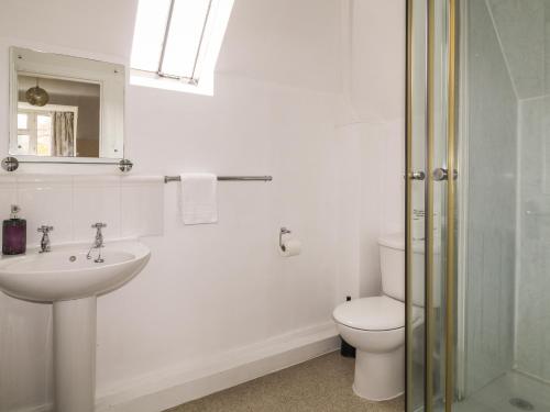 a white bathroom with a toilet and a sink at Aldrich Cottage in Kilmersdon