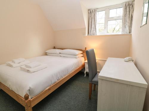 ein Schlafzimmer mit Bett, Schreibtisch und Fenster in der Unterkunft Aldrich Cottage in Kilmersdon