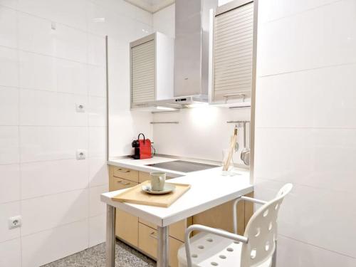 a white kitchen with a table and a chair at GRAN VÍA Bilbao & Parking gratis by ALOHA Bilbao in Bilbao