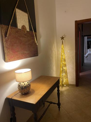 a room with a table with a lamp and a christmas tree at Medea Home in Carosino