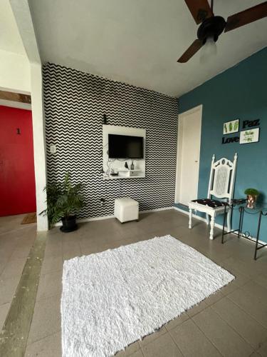 uma sala de estar com uma televisão e um tapete branco em Aconchego Penedo em Penedo