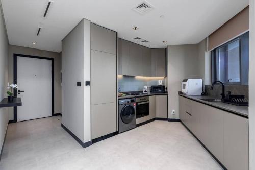 een keuken met witte kasten en een wasmachine en droger bij Waves Holiday Homes - 15 Northside, Tower 1, Two Bedroom in Dubai