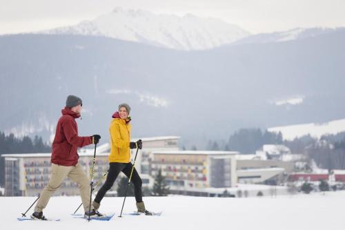 two people walking in the snow on skis at Aldiana Club Salzkammergut und GrimmingTherme in Bad Mitterndorf