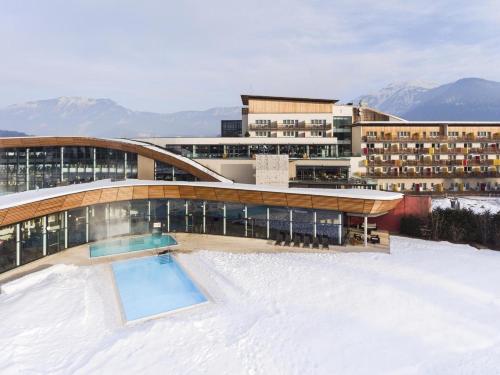 a building with a swimming pool in the snow at Aldiana Club Salzkammergut und GrimmingTherme in Bad Mitterndorf
