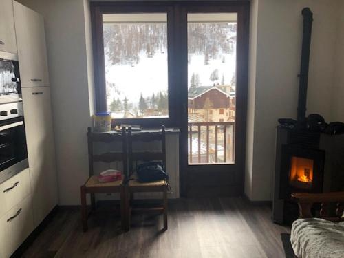 a living room with a fireplace and a window with a view at Appartamento G&G in Pontechianale