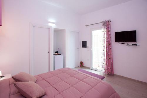 1 dormitorio con cama rosa y TV en Affittacamere LE RONDINI, en Domus de Maria
