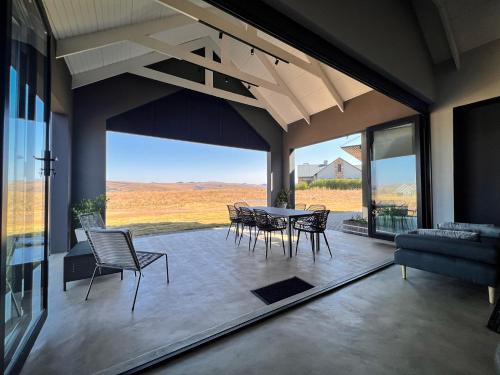 a dining room with a table and chairs and a large window at Highland Gate Range View in Dullstroom
