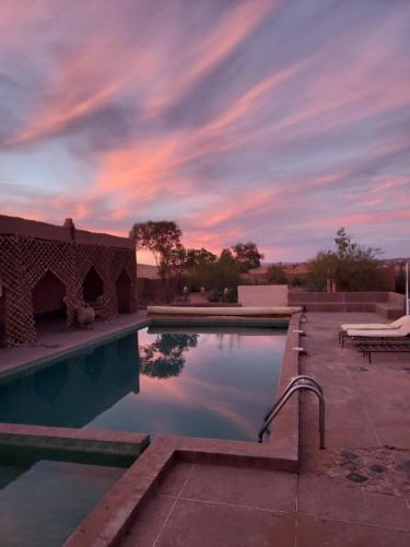 una piscina con puesta de sol en el fondo en Riad ma bonne étoile, en Oulad Driss