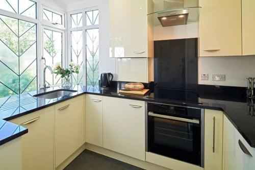 a kitchen with white cabinets and a black counter top at BOURNECOAST: GROUND FLOOR - GARDEN - WIFI - FM6096 in Iford