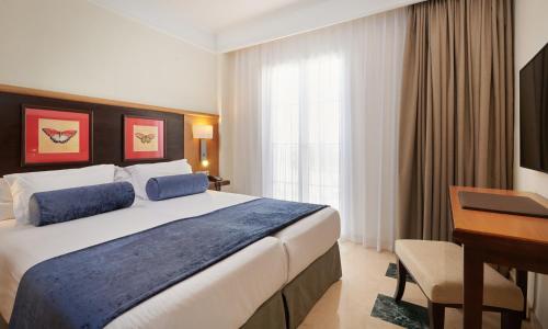 a hotel room with a large bed and a desk at Grupotel Playa de Palma Suites & Spa in Playa de Palma