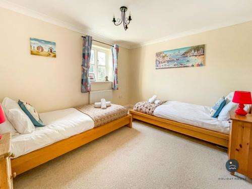 two twin beds in a room with a window at Wildflower Cottage - Sutton Poyntz in Preston