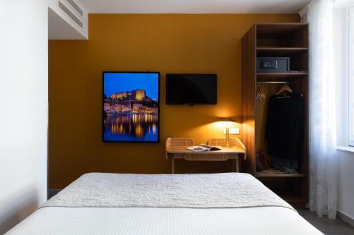 a bedroom with a bed and a tv on a wall at Best Western Hotel du Roy d'Aragon in Bonifacio