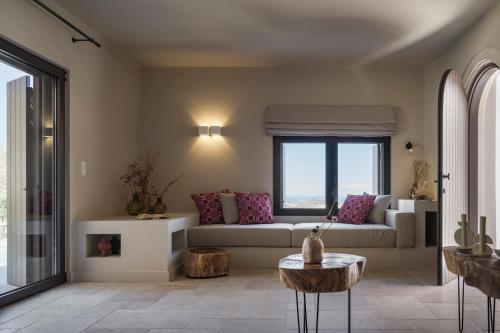 a living room with a couch and a large window at Askianos Luxury Villas - An Oasis of Harmony & Elegance in Lístaros
