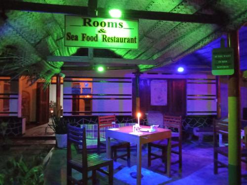 a restaurant with a table and chairs and a sign at Viraj's Garden in Tangalle
