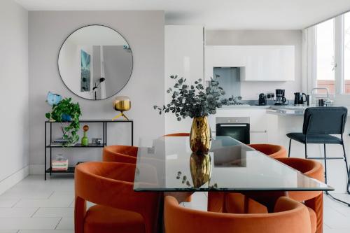 uma sala de jantar com uma mesa de vidro e cadeiras laranja em Divine Views from a Breathtaking LuxXe City Penthouse for a Gracious Life Style em Londres