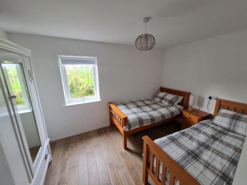 Habitación pequeña con 2 camas y 2 ventanas en The Poets Cottage, en Ballymena