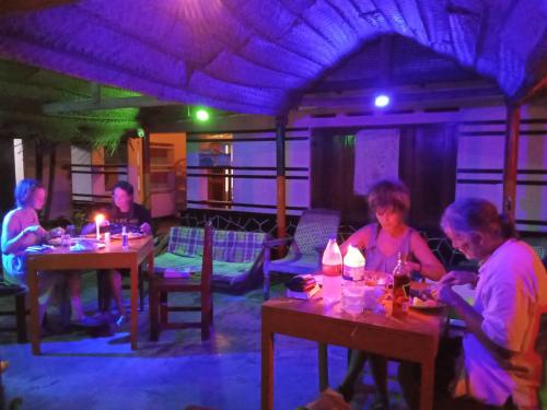 un grupo de personas sentadas en mesas en un restaurante en Viraj's Garden, en Tangalle