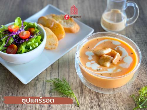 a bowl of soup with a salad and a plate of food at tt Residence in Chachoengsao