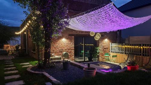 un patio trasero con una red púrpura colgando de una casa en GARY Suite - Studio Cosy, Spa et jardin privatif à 4 min de Cambrai, en Awoingt