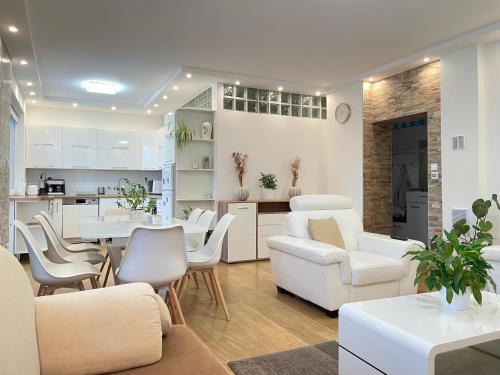 a living room with white furniture and a kitchen at Ildikó lak in Vonyarcvashegy