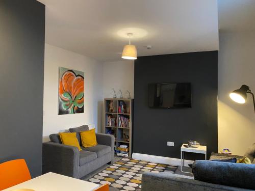 a living room with a couch and a tv on a wall at Mia's Place Chester in Chester
