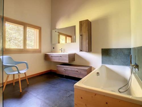 a bathroom with a tub and a sink and a chair at Le Vivier in Saint-Gervais-les-Bains