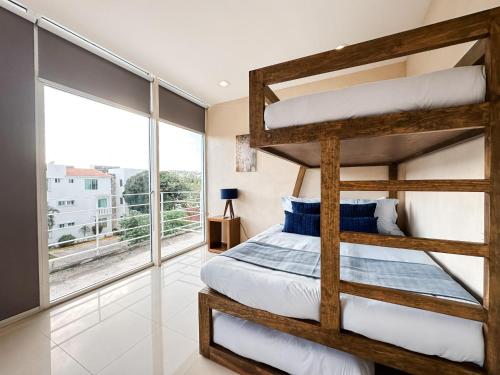um quarto com 2 beliches e uma grande janela em AZULB15 3 Bedroom Playacar Phase II em Playa del Carmen