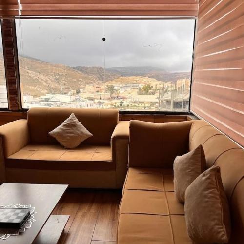 um sofá num quarto com uma grande janela em Petra inbox Hostel em Wadi Musa