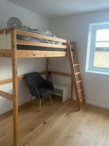 1 dormitorio con litera, silla y ventana en Especial fin de semana, en Rødovre