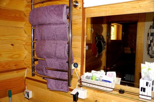 a purple towel hanging on a wall in front of a mirror at Kettu Holl Cottage in Taipalsaari
