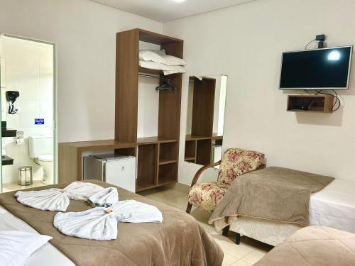 um quarto de hospital com duas camas e uma cadeira em Pousada Rainha Dos Lagos em Capitólio