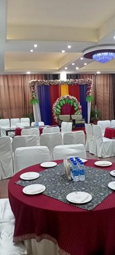 a banquet hall with white chairs and a table with plates at Mg Regency in Baddi