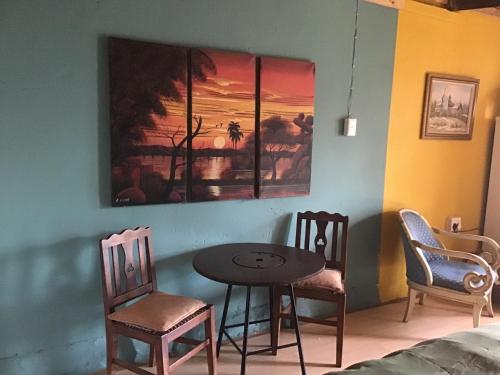 a table and chairs in a room with a painting on the wall at The shack life in Rensburgdorp