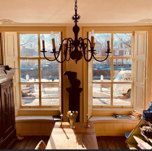 a chandelier in a room with windows and a table at B&B Röderhaus Goedereede in Goedereede