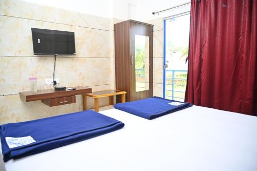 a bedroom with two beds and a tv on the wall at Blue Pearl Beach Guest House in Māvalli