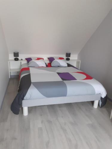 a bedroom with a bed with a colorful comforter and pillows at Hébergement individuel chez particulier proche 24h du Mans in La Milesse